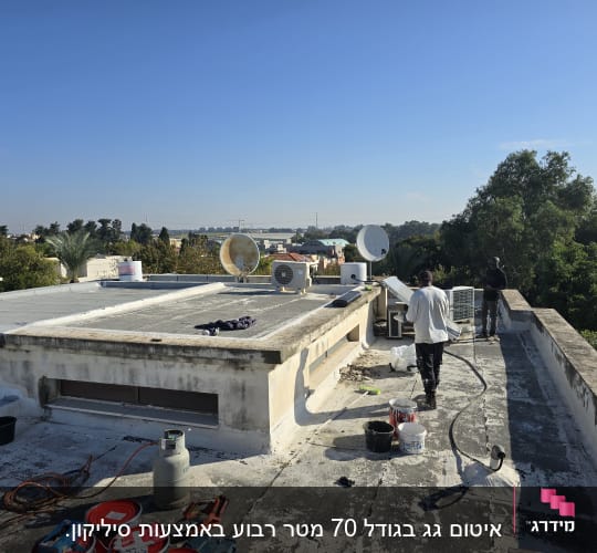 עובדים על גג עם כלים וחומרי איטום